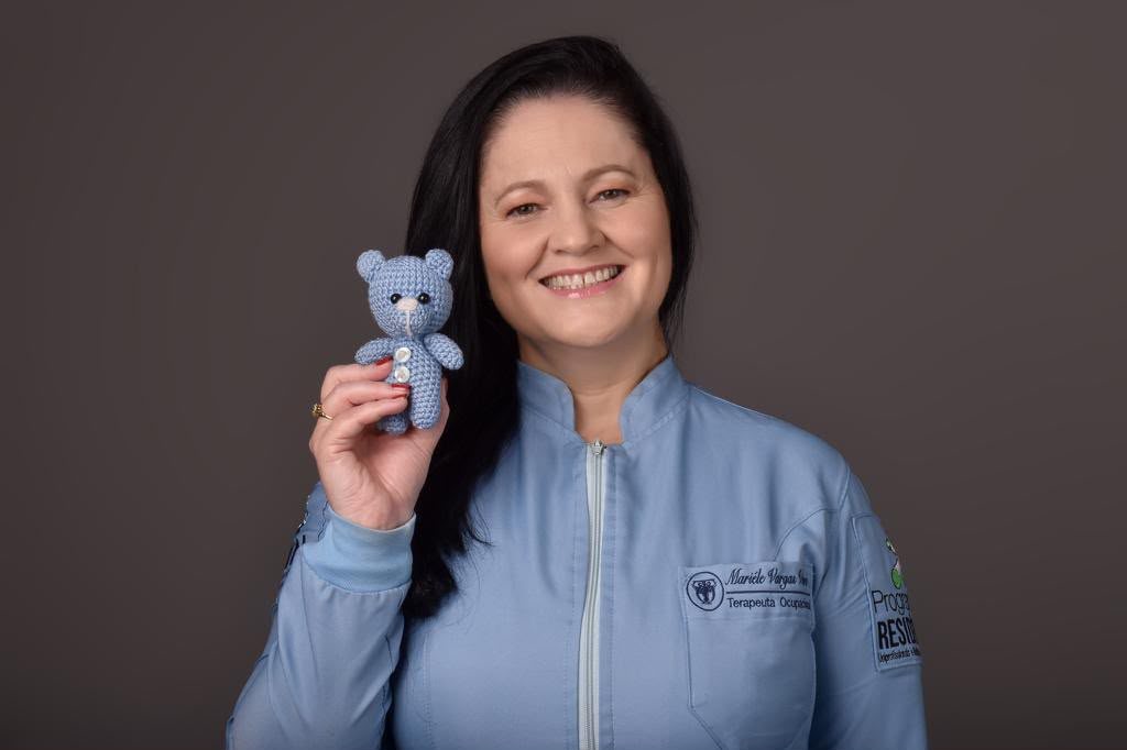 Mariéle Vieira, Terapeuta Ocupacional, sorrindo e segurando um ursinho de pelúcia